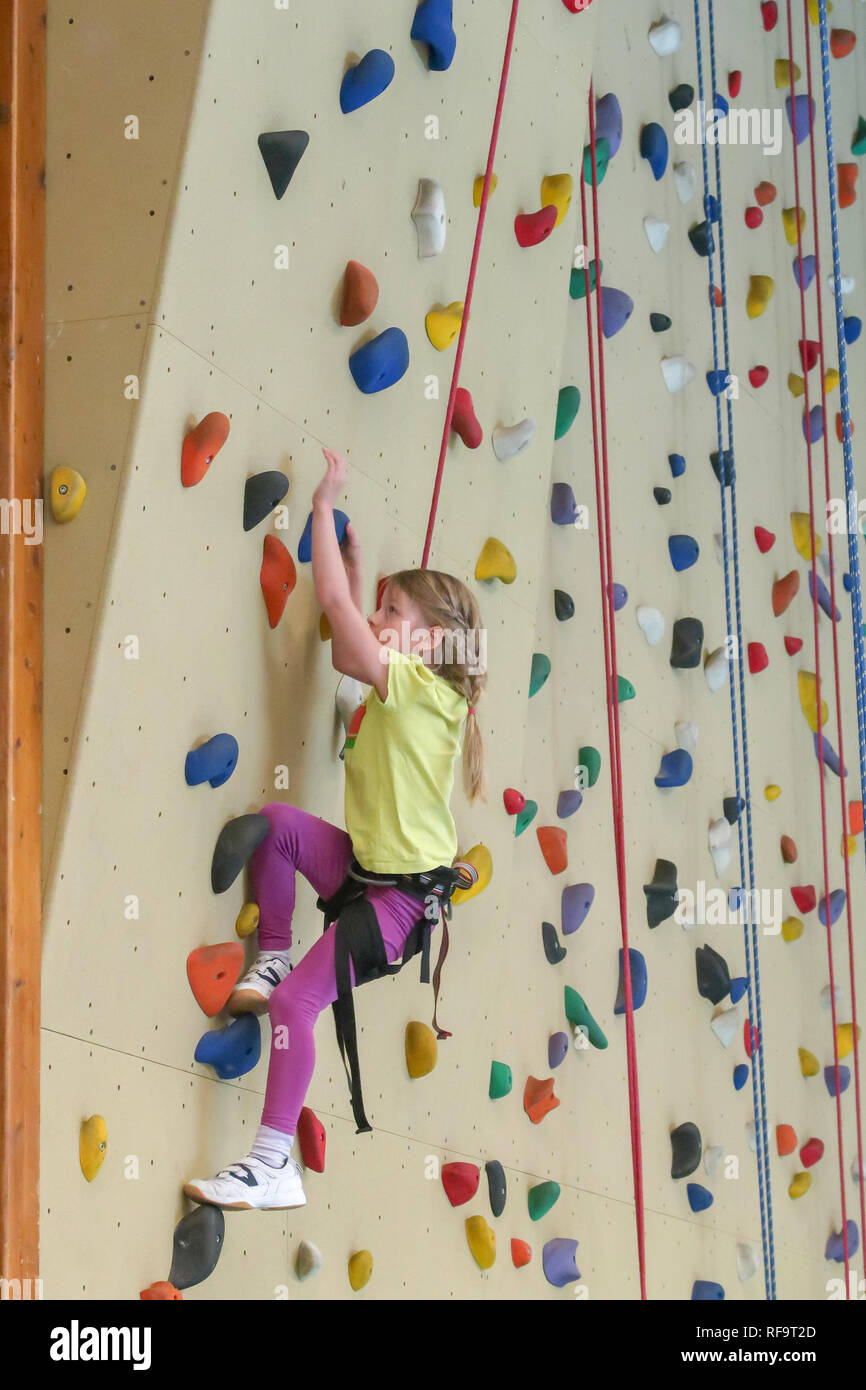 Un 7 anno vecchia ragazza si arrampica su una parete di arrampicata in una sporgenza Foto Stock