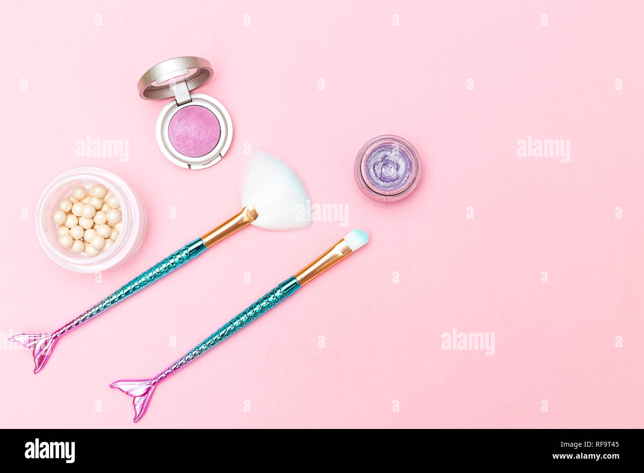 Spazzola per il trucco mermaid e ombretto su sfondo rosa. Spazio di copia Foto Stock