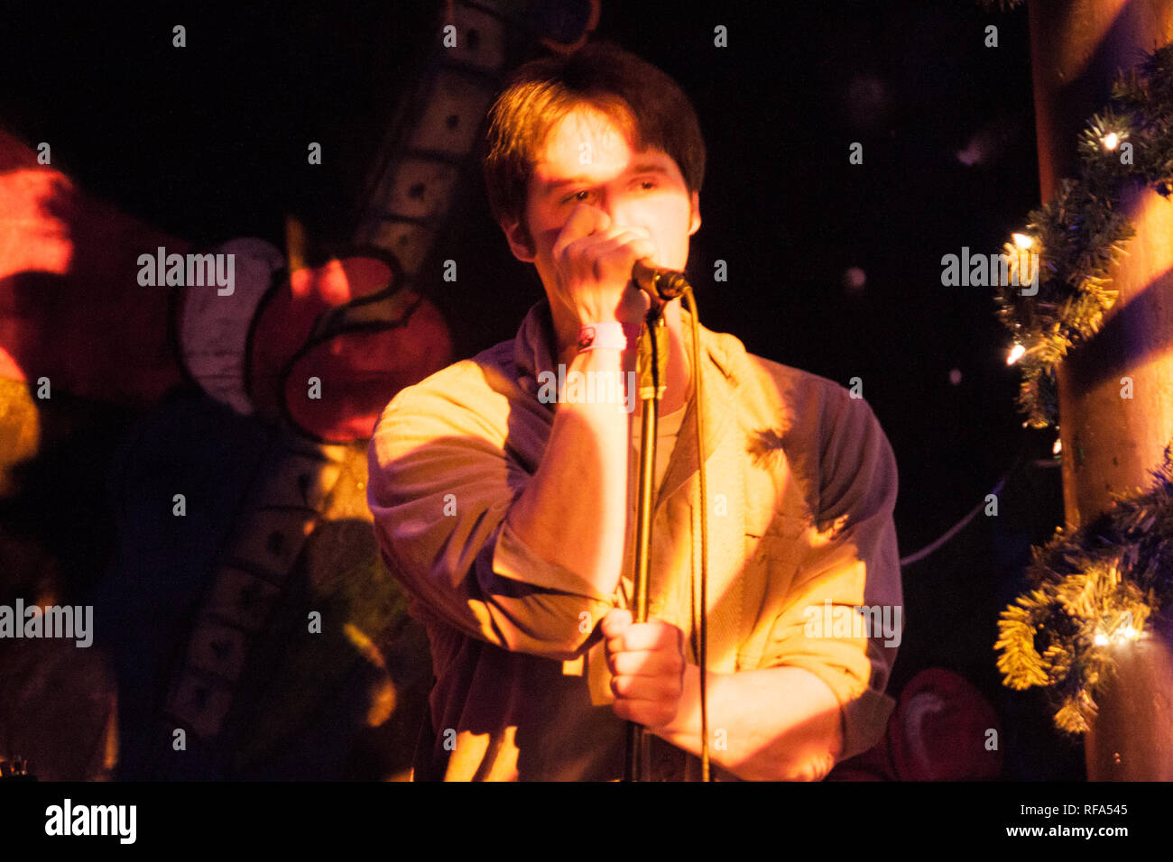 Il cantante in una band canto sul palco con colorate psichedeliche come la luce che incide su di essi in un spettacolo musicale durante le vacanze. Foto Stock
