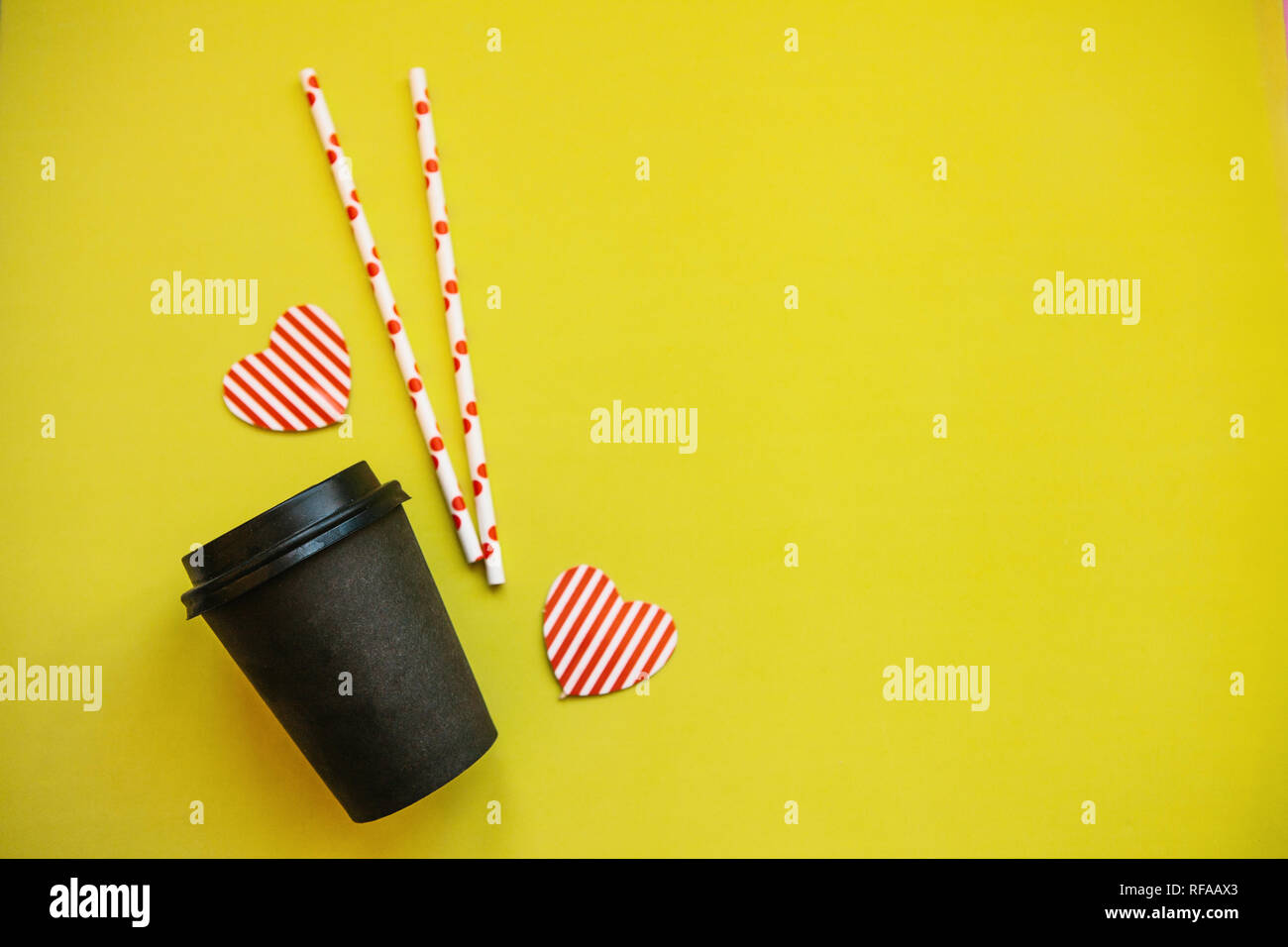 La tazza con il caffè, tubuli e cuori decorativi su uno sfondo giallo. Vicino a place per il testo. Foto Stock