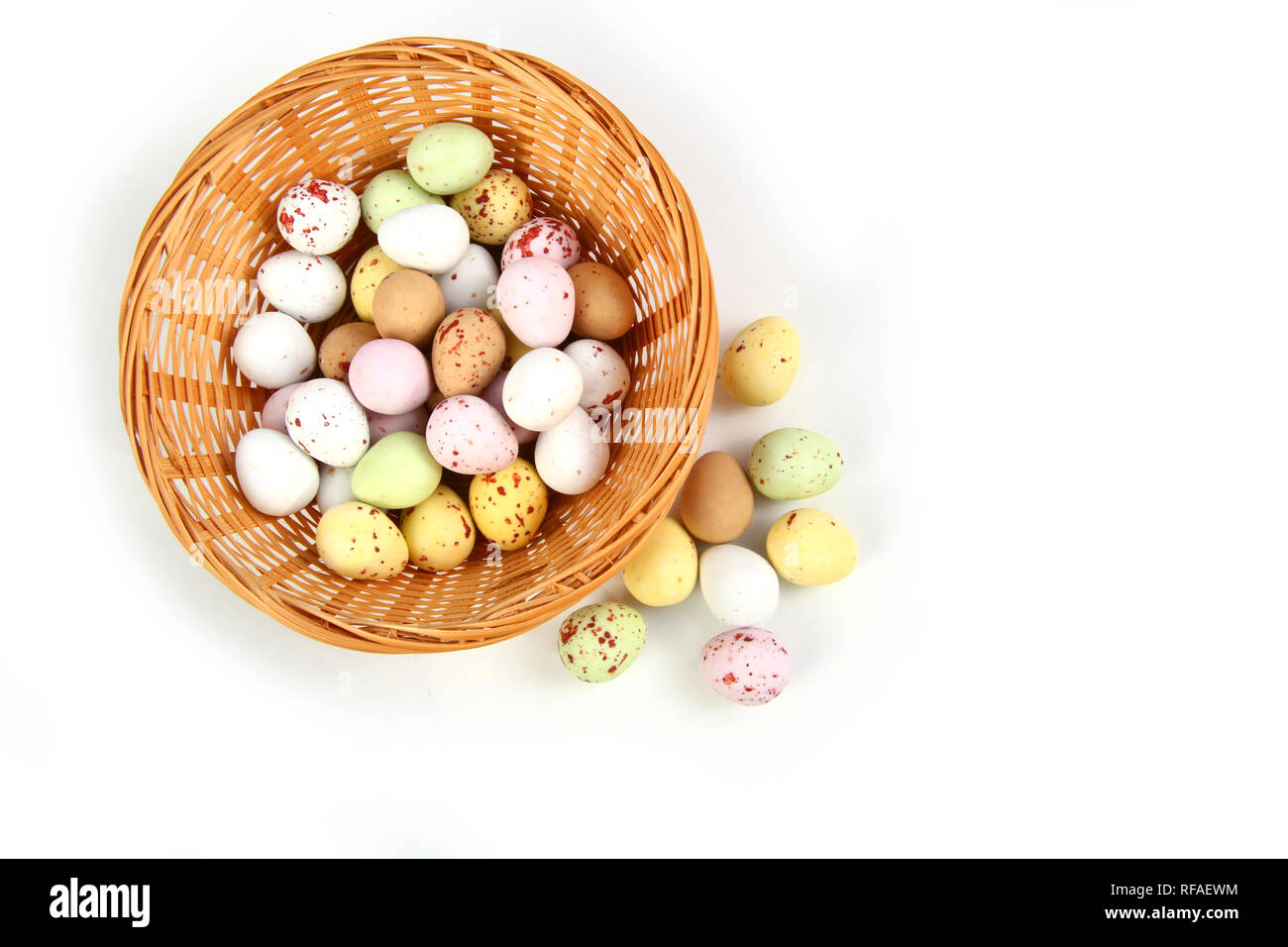 Il cioccolato mini uova di Pasqua in paglia o cesto di vimini contro uno sfondo bianco Foto Stock