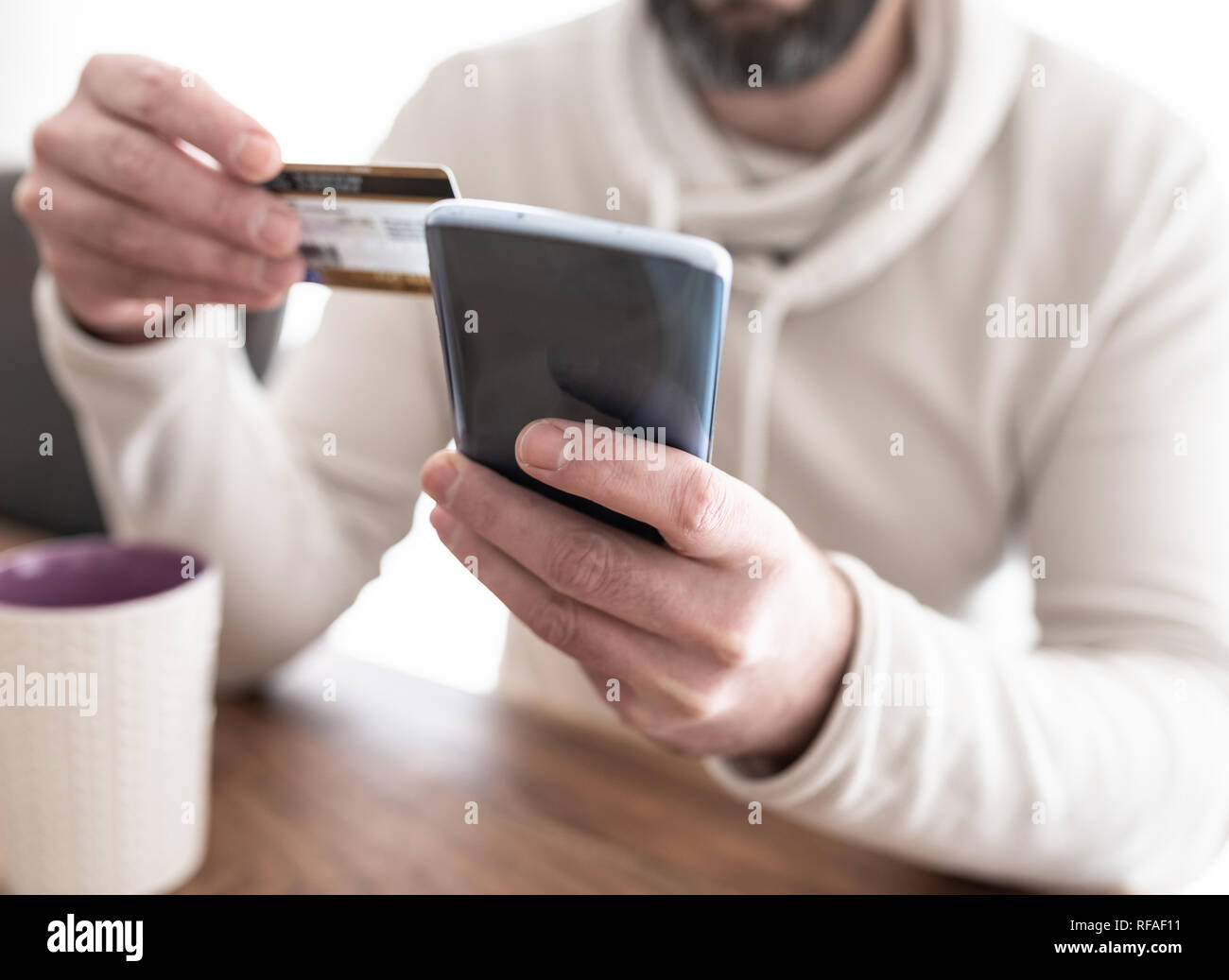 L'uomo immettendo le informazioni della carta di credito sullo smartphone Foto Stock