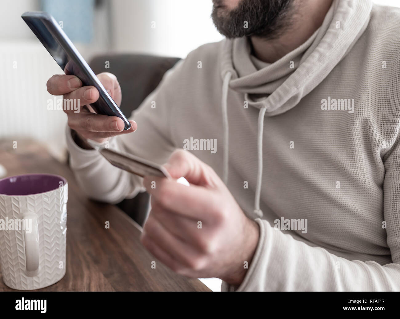 Close-up di uomo immettendo le informazioni della carta di credito mentre lo shopping su Internet sullo smartphone Foto Stock