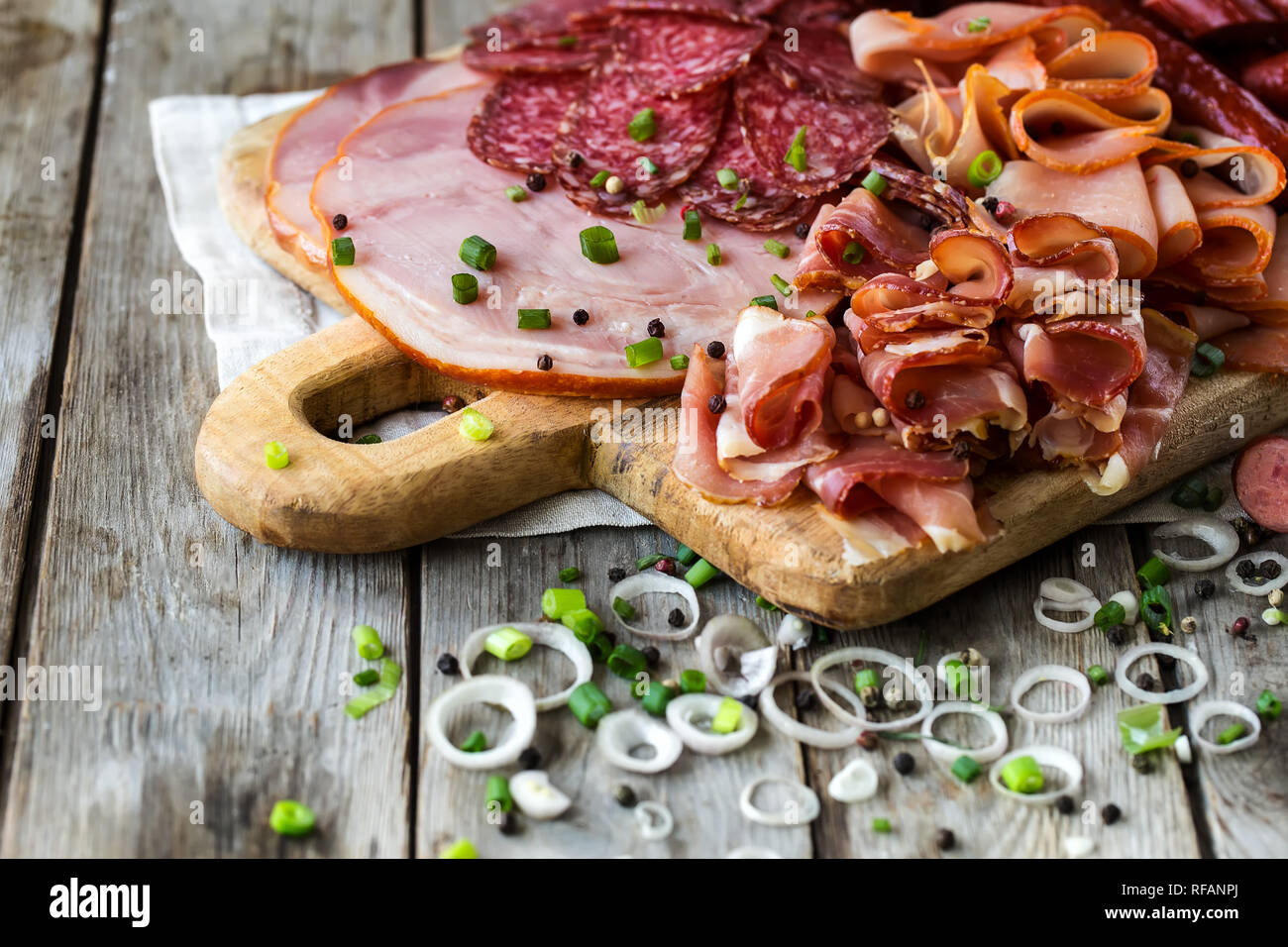 Mix di antipasti di carne - salame, prosciutto, tacchino affumicato, salsicce e prosciutto - rustico sfondo di legno Foto Stock