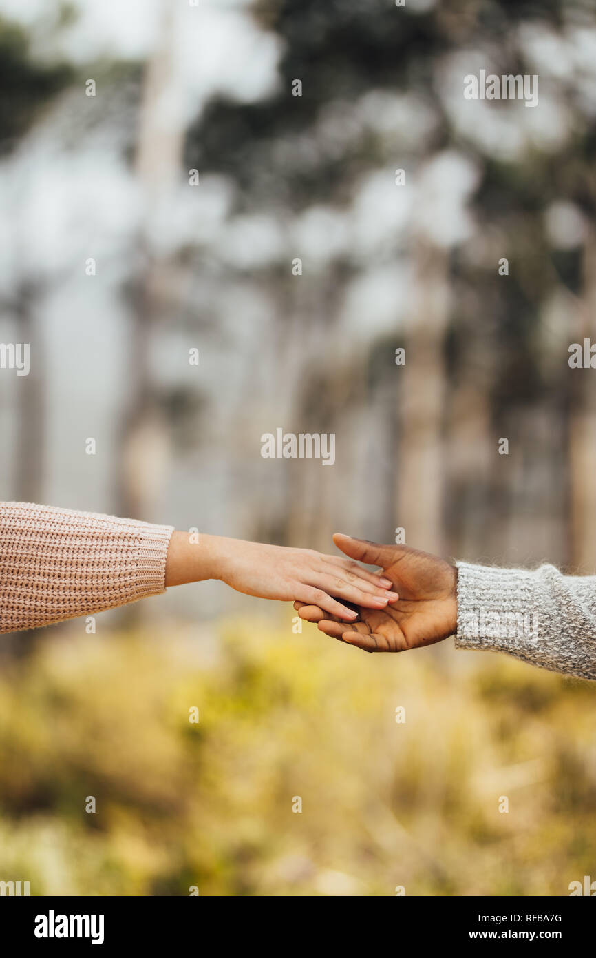 Interracial giovane mani di raggiungere ogni altro all'esterno. Giovane si avvicinano gli uni agli altri e tenendo le mani. Foto Stock