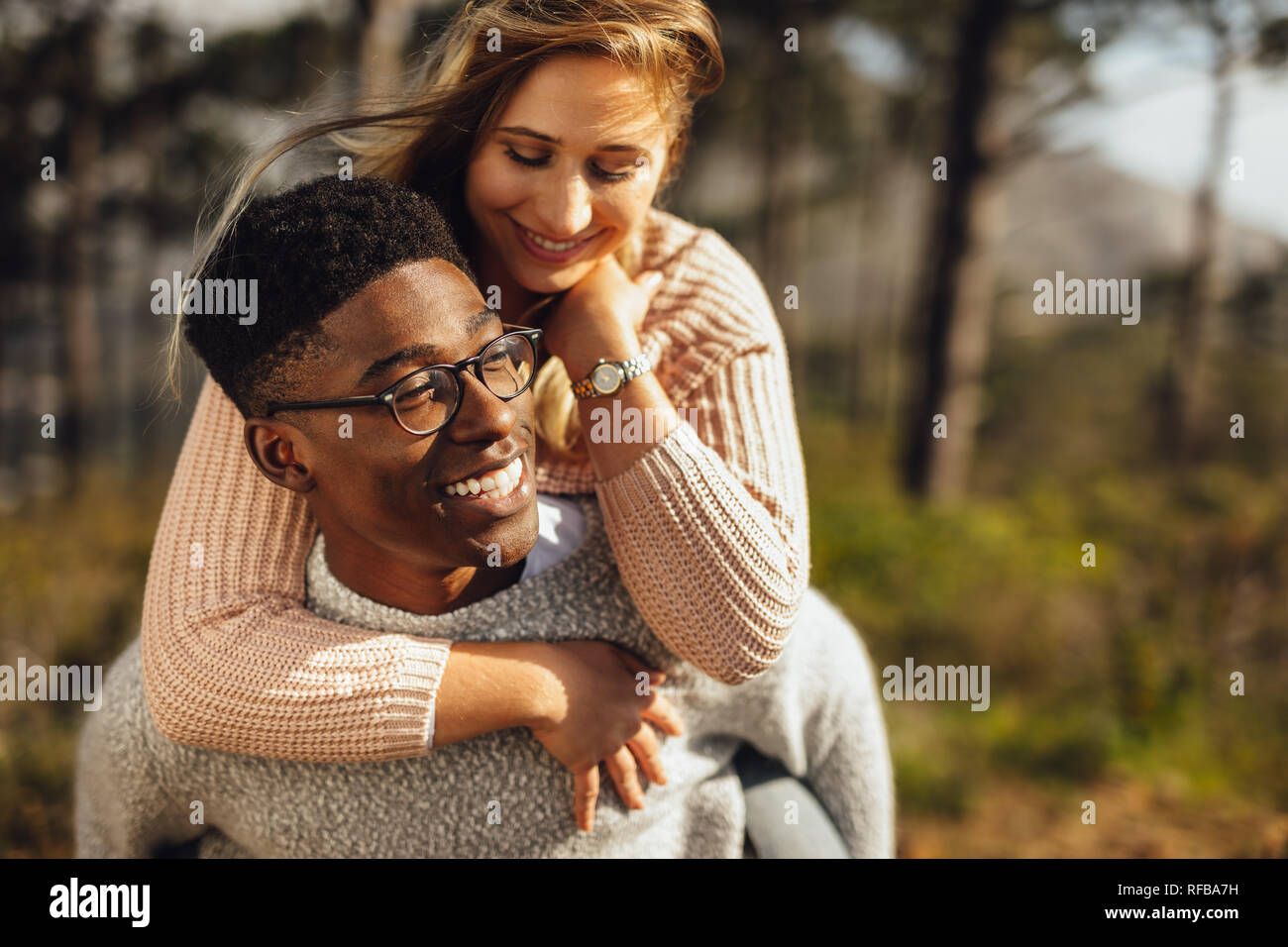 L uomo dando piggyback ride a hiss ragazza all'esterno. Coppia romantica che si diverte all'esterno. Foto Stock