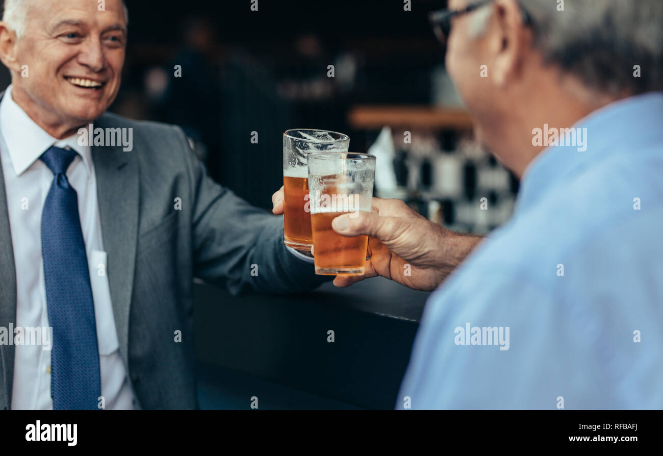 Uomini d'affari anziani che brindano i bicchieri di birra al bar dopo il lavoro. i professionisti del lavoro bevono un drink al bar dopo il lavoro. Foto Stock