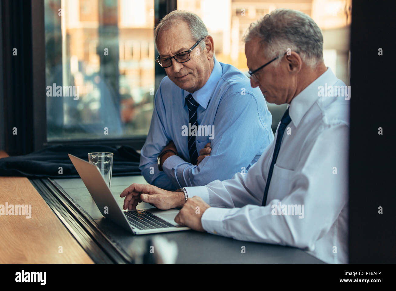 Due imprenditori lavora su un computer portatile presso il cafe contatore. Due senior business professional guardando al computer portatile presso la caffetteria. Foto Stock