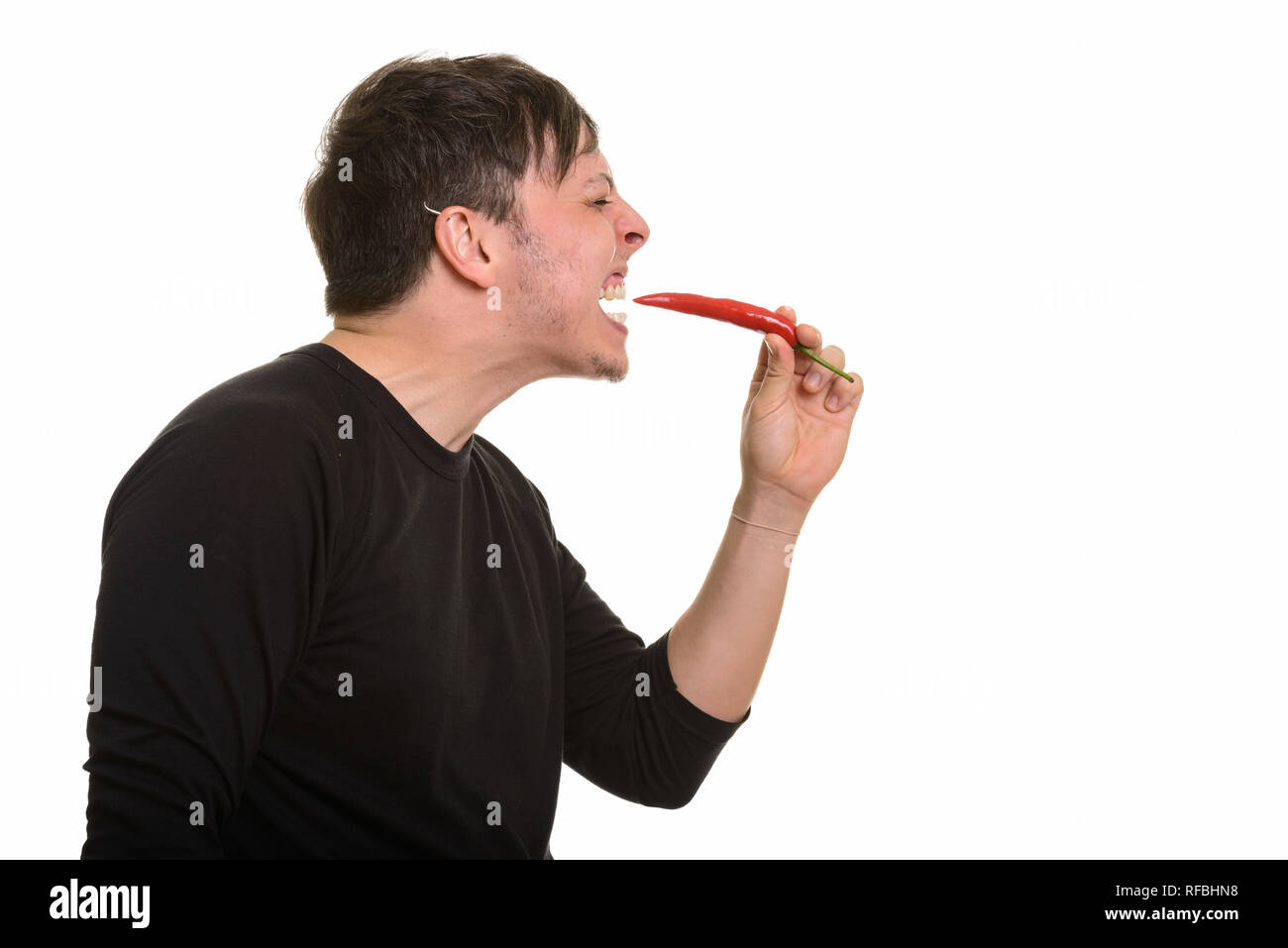 Vista di profilo di Crazy uomo caucasico di mangiare il pepe rosso Foto Stock