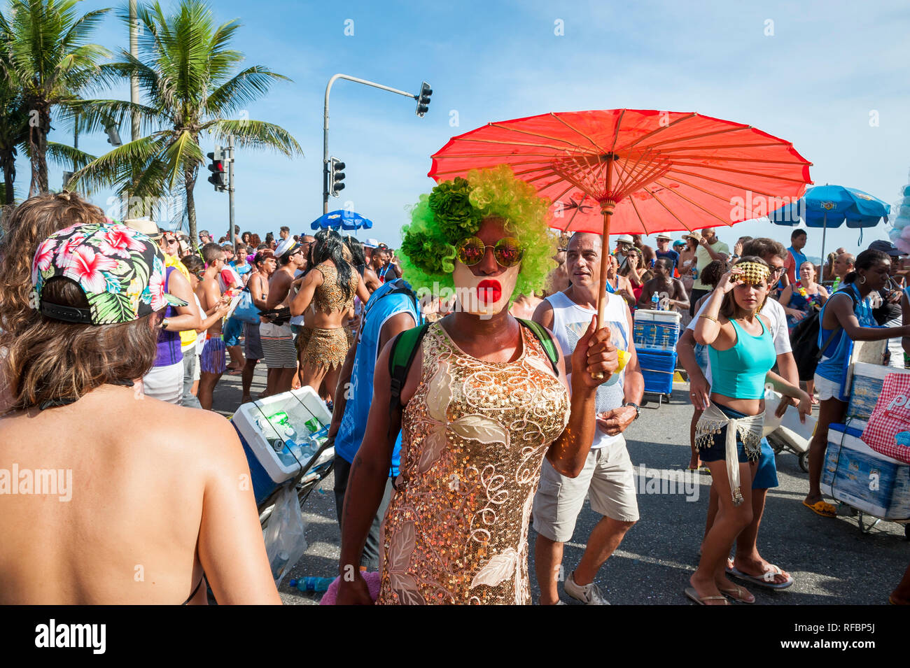 RIO DE JANEIRO - Febbraio 07, 2016: un uomo brasiliano in femminile fiammeggiante trascinare costume passeggiate con un ombrellone rosso al Carnevale street party in Ipanema Foto Stock