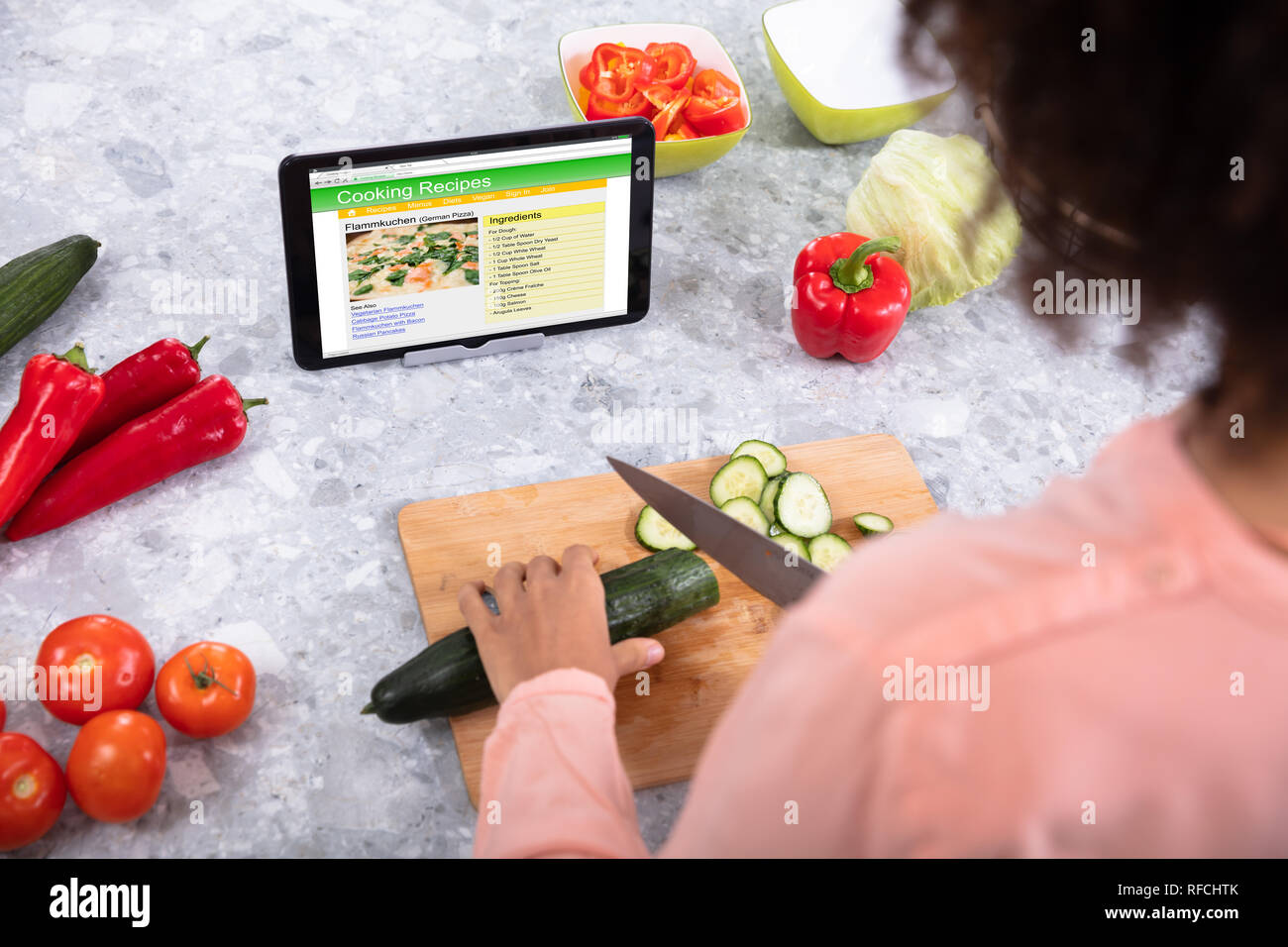 Donna di mano cavolo di taglio sul tagliere con le ricette di cucina su tavoletta digitale schermo Foto Stock