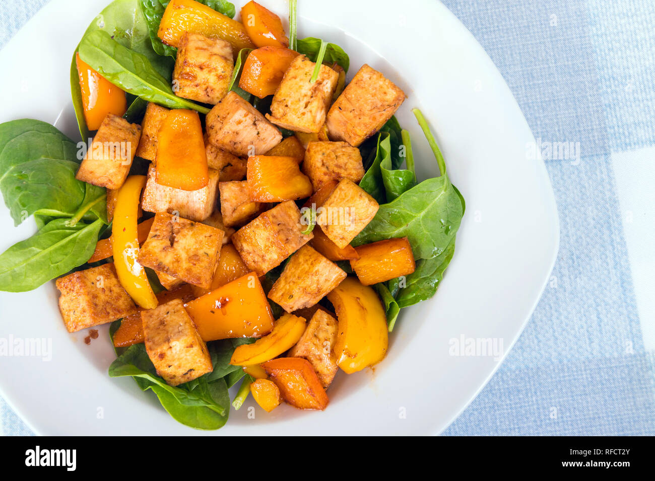 Il tofu in agrodolce con peperoni su letto di spinaci Foto Stock