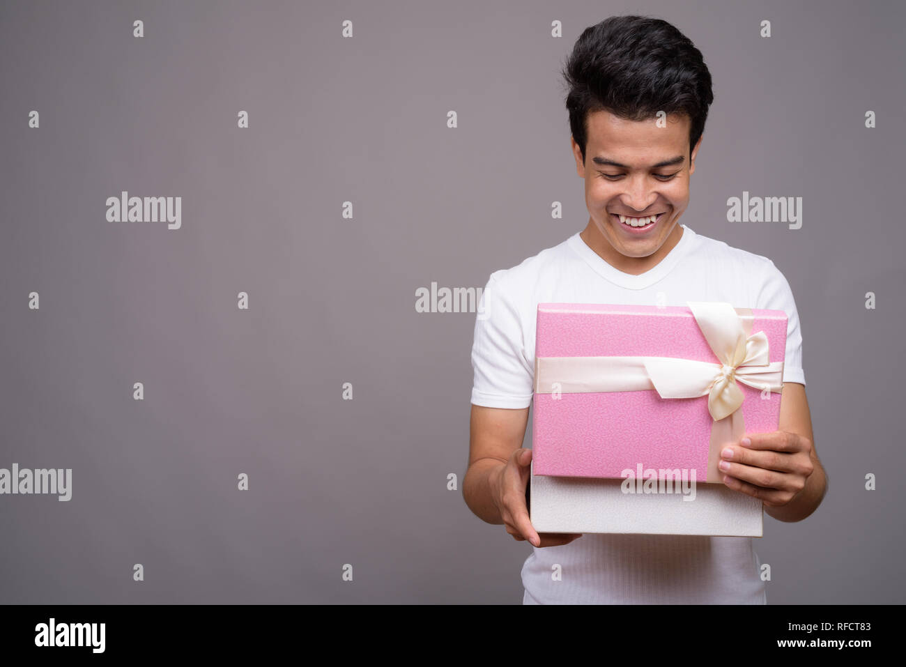 Ritratto di giovane uomo asiatico contro uno sfondo grigio Foto Stock