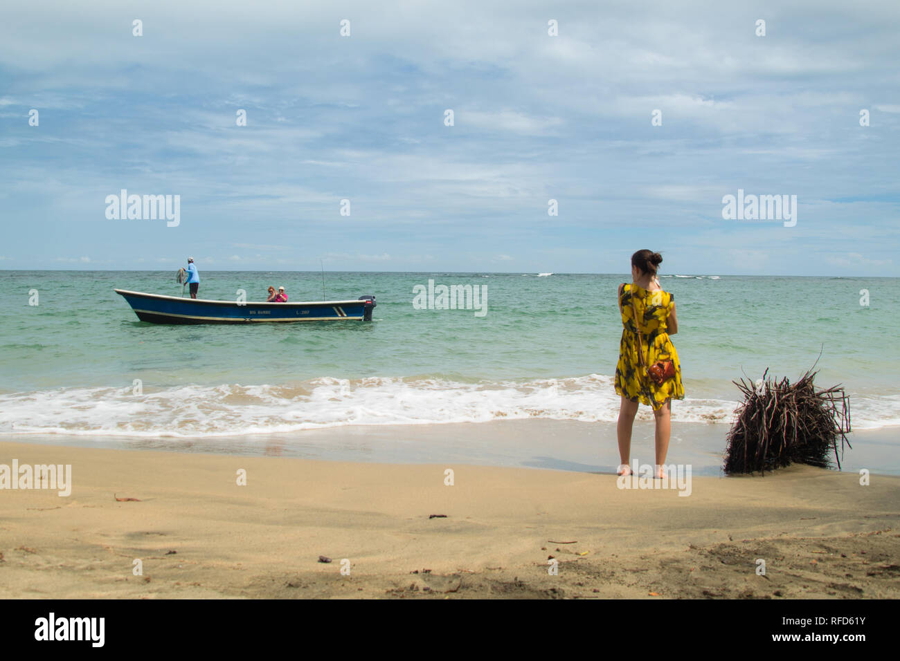 Una bella foto orizzontale di una madre e figlio in piedi su una spiaggia di sabbia a guardare indietro a lasciare la barca al tropical Manzanillo beach, Costa Rica Foto Stock