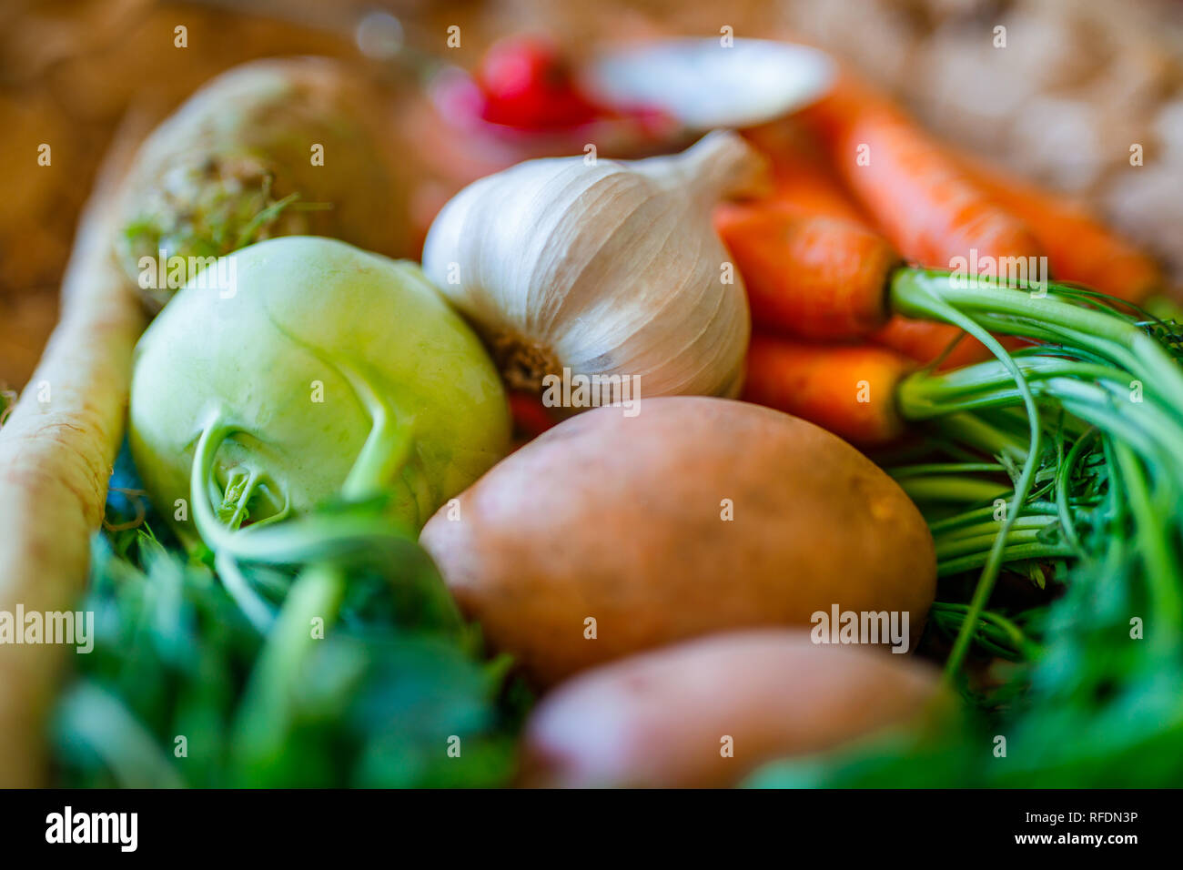 Carote e sedano rapa, peperoncino e aglio ortaggi freschi sul recipiente di vimini e preparazione per la cottura con lo sfondo sfocato Foto Stock