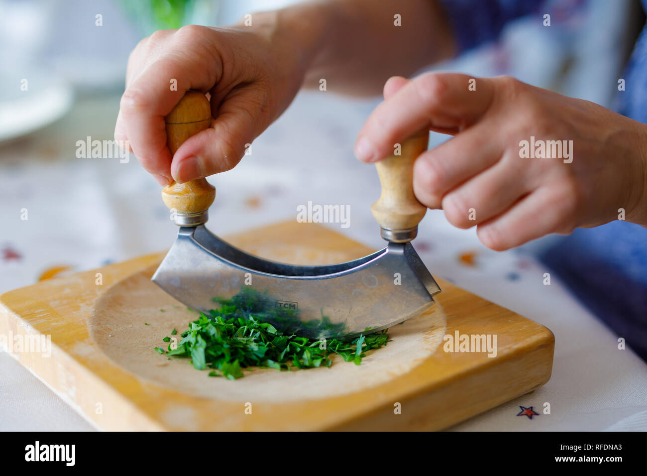 Una donna trita il prezzemolo su un tagliere di legno in cucina Foto stock  - Alamy