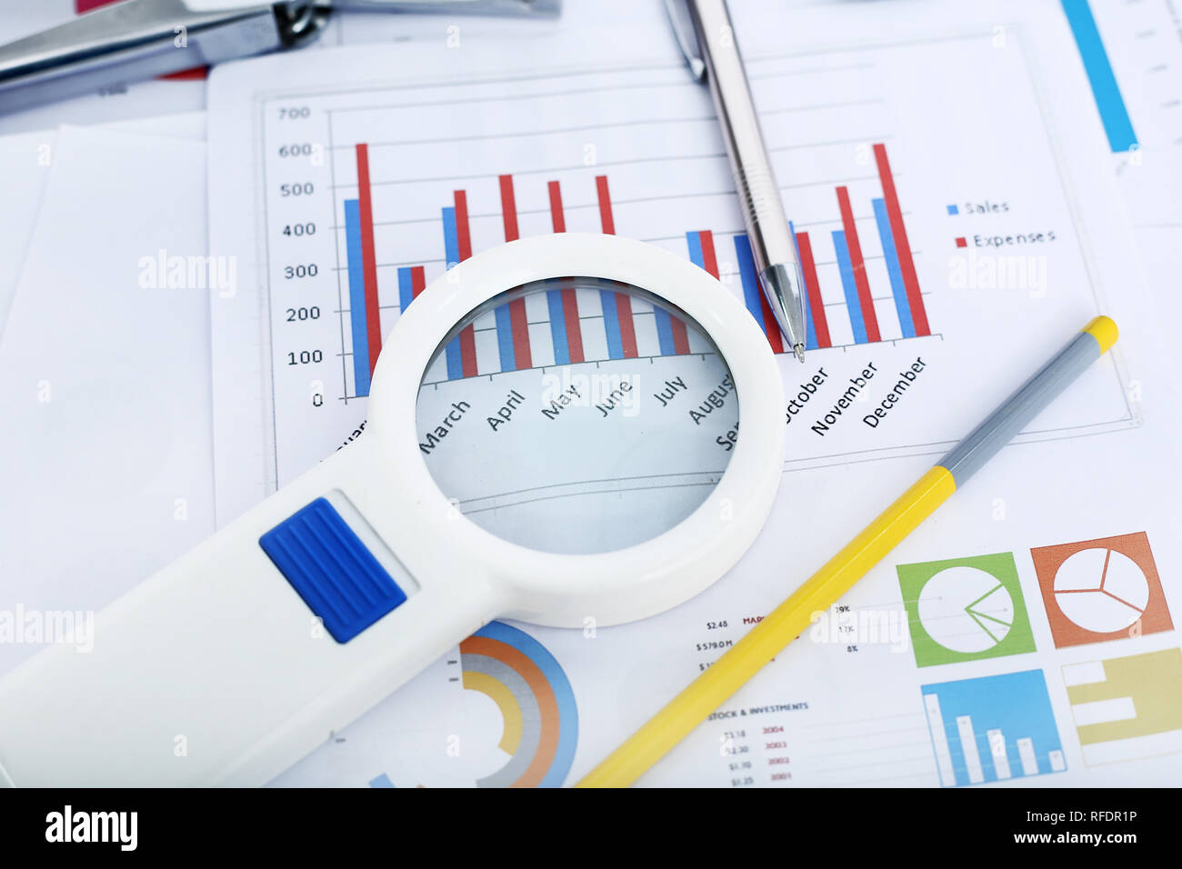 Immagine della carta finanziaria, cucitrice, penna, matita e lente di ingrandimento. Foto Stock
