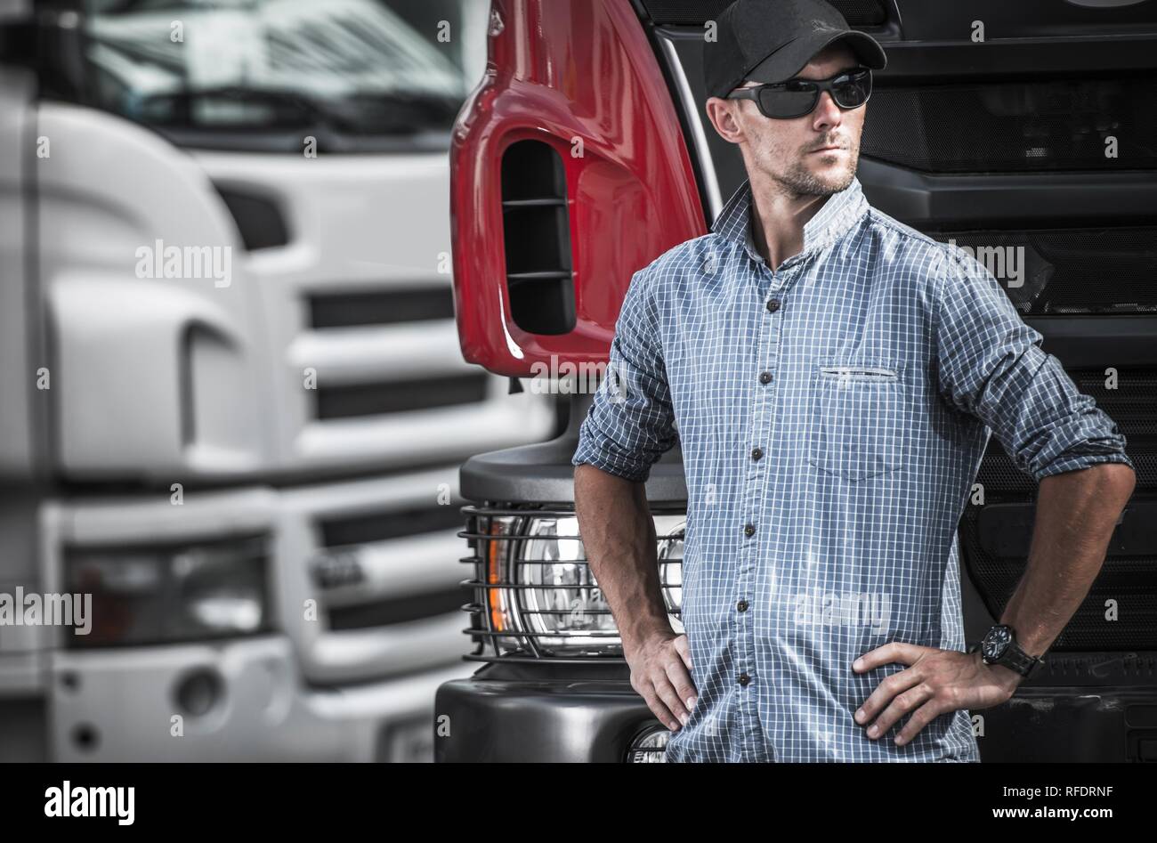 Trucker e del settore dei trasporti. Uomini caucasici nella sua 30s nella parte anteriore della sua Semi carrello. Foto Stock