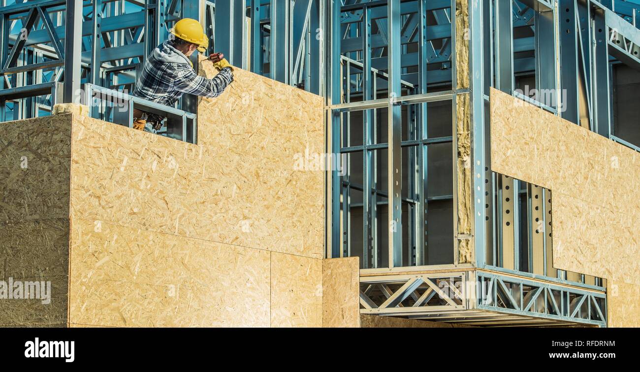 Il lavoratore e il sito in costruzione. Lo scheletro del telaio in acciaio l'installazione. Foto Stock