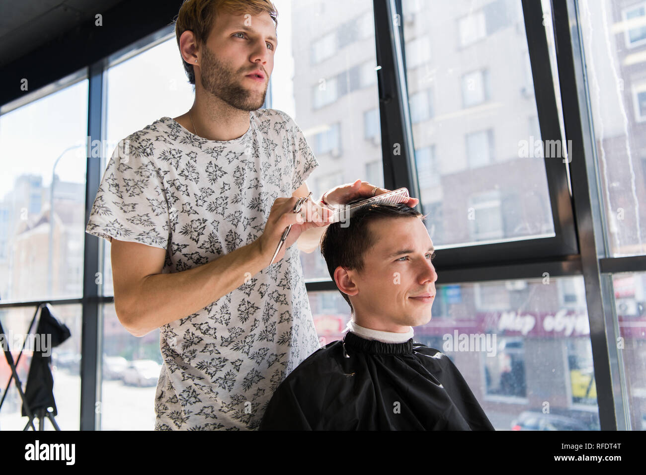 Parrucchiere non i capelli con il pettine di bello cliente soddisfatto in professional parrucchiere Foto Stock
