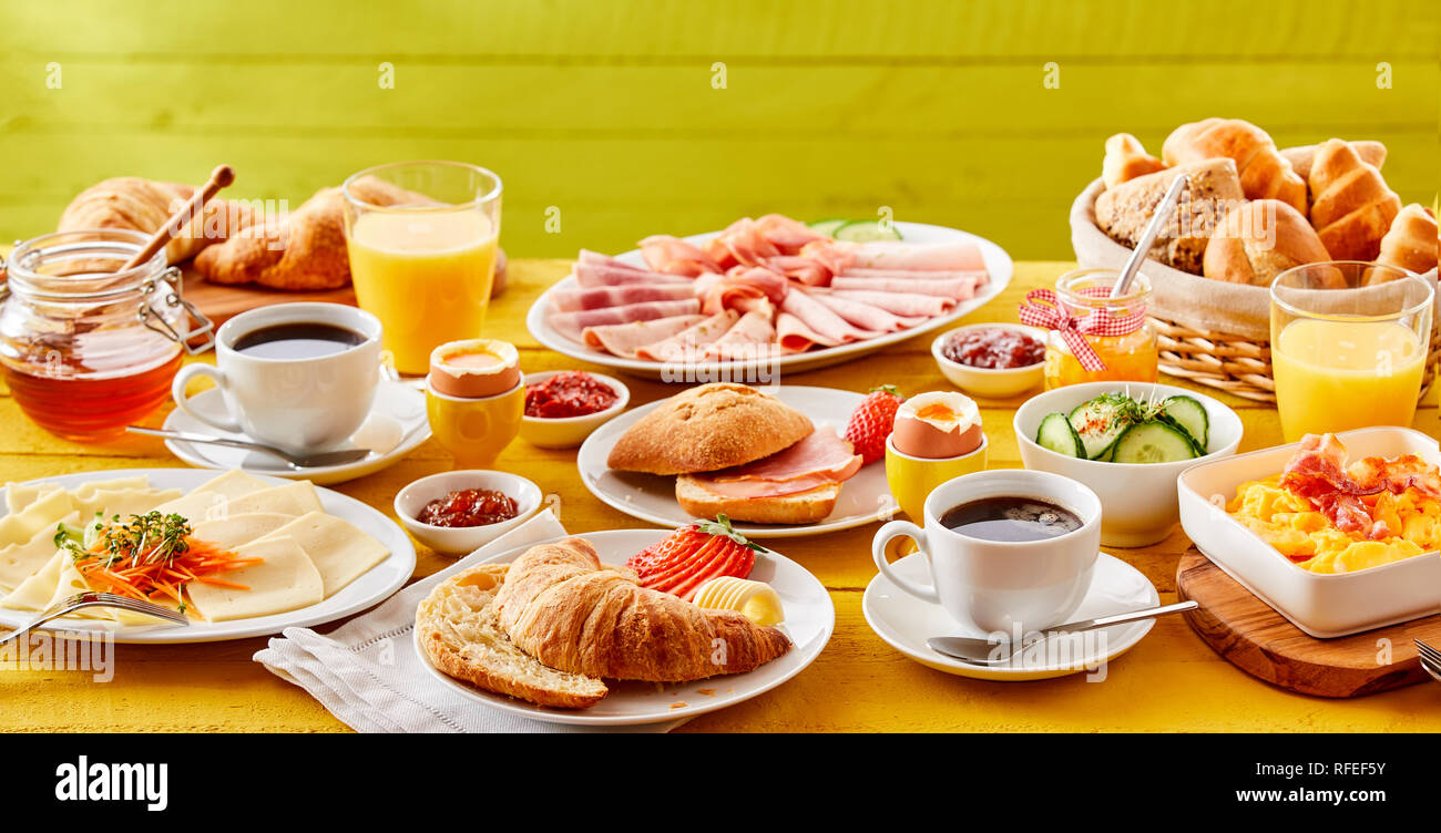Spring Colazione banner con una scelta di cibi che includono un cornetto, am o pancetta rotolo, frittata, freddo di tagli di carne, formaggio, marmellate miele e servita con o Foto Stock