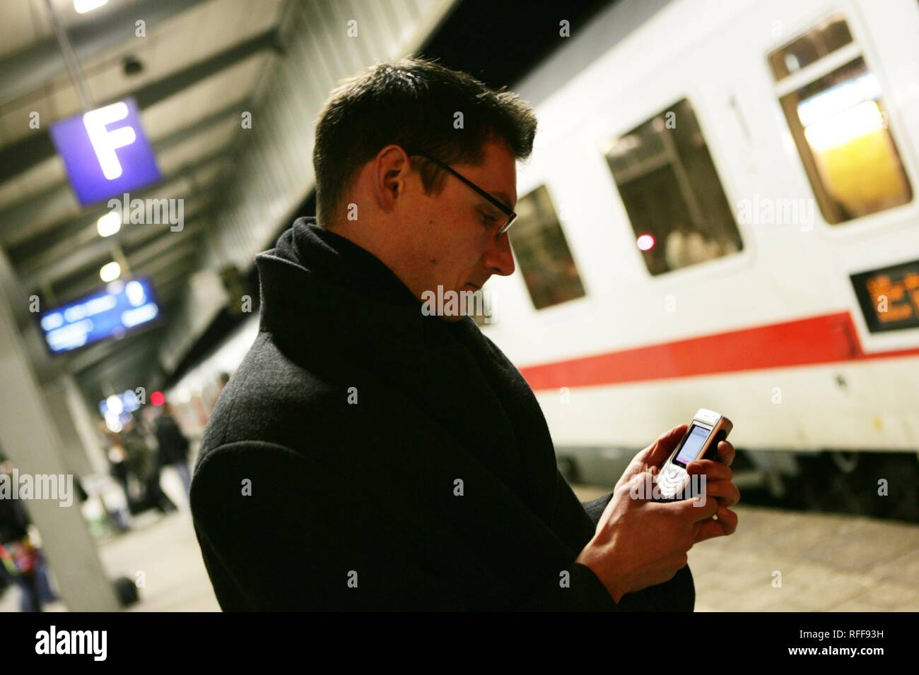 DEU Germania uomo con un telefono mobile sulla piattaforma di una stazione ferroviaria. | Foto Stock