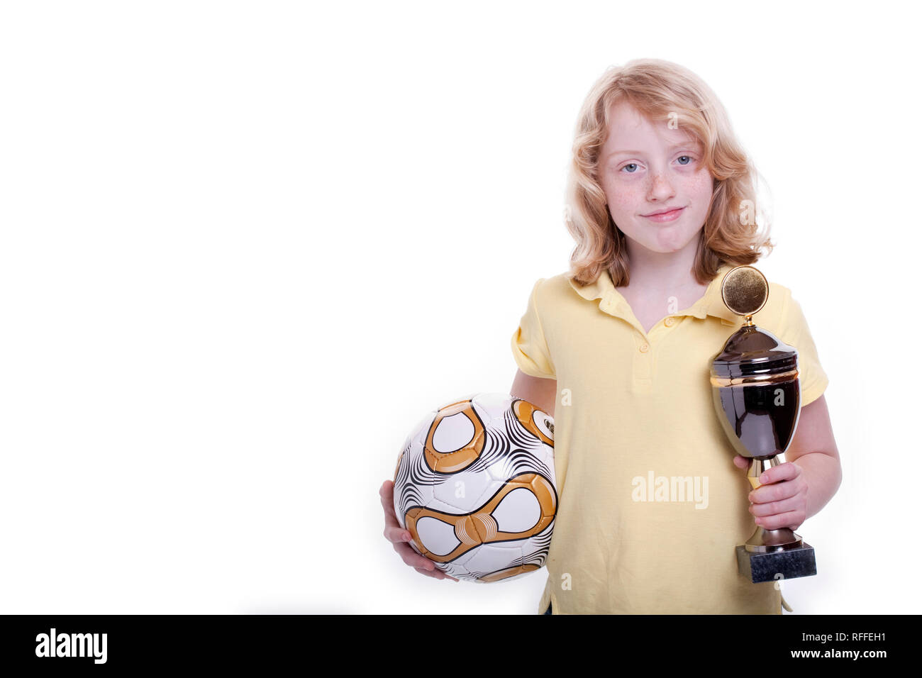 Piccola ragazza con un campo di calcio e la coppa in mano Foto Stock