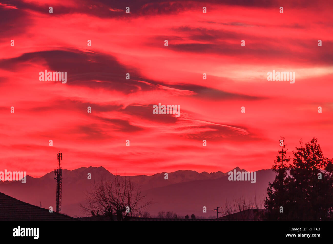 Un paesaggio al tramonto con le montagne e gli alberi disegnati in cielo /uno spettacolare tramonto sulle montagne dipinge il cielo di Orange Foto Stock