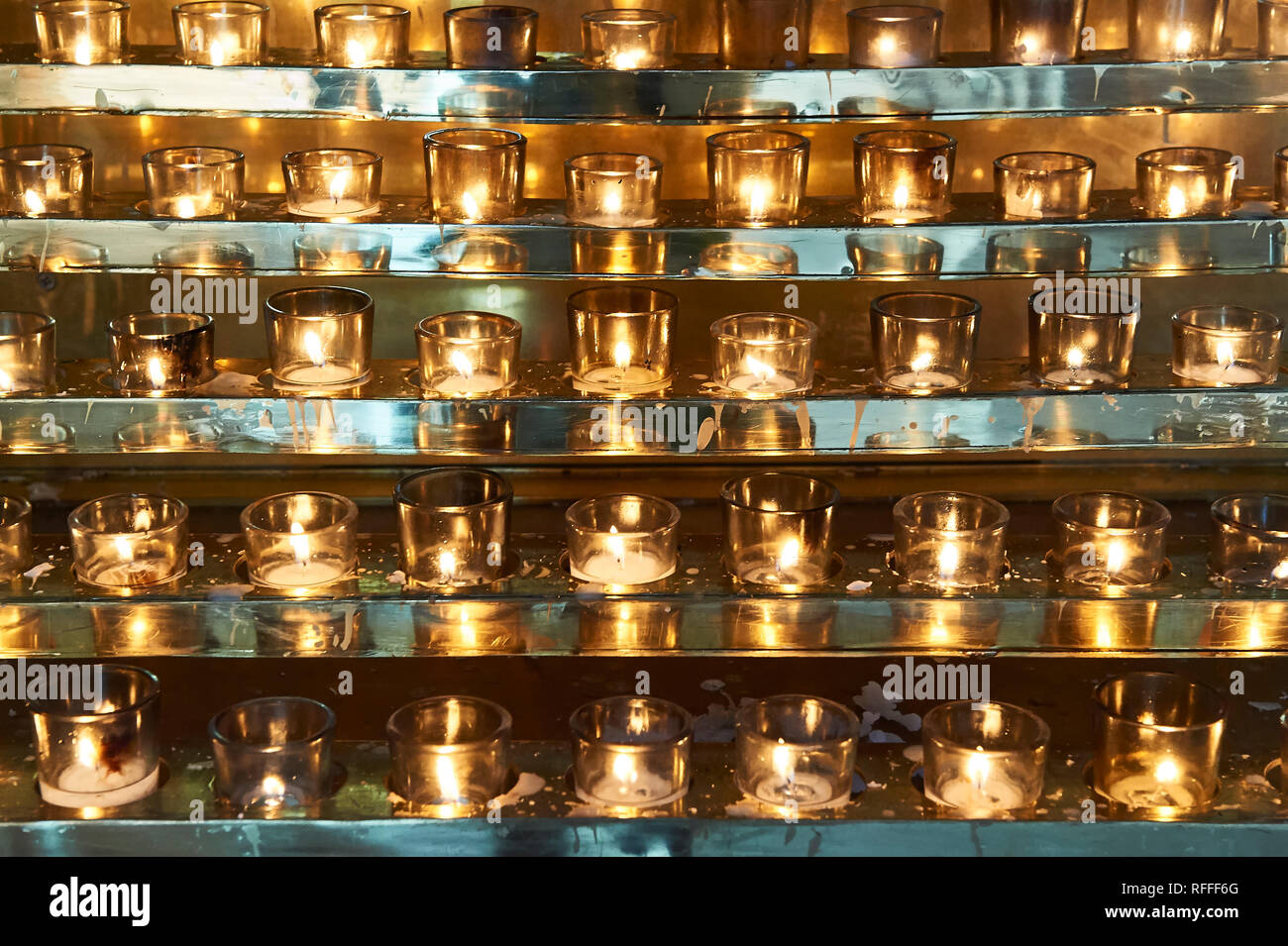 Molte candele schierate nel Santo Rosario nella cattedrale di Vancouver, Canada, splendente d'oro davanti a uno sfondo color argento Foto Stock