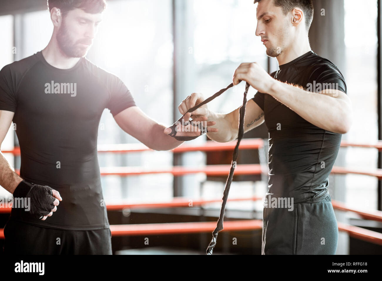 Trainer bendaggio di avvolgimento sul polso di un uomo, la preparazione per il pugilato il pugilato ring in palestra Foto Stock