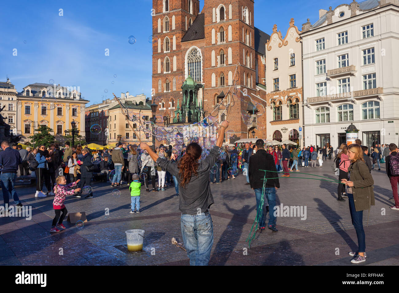 La Polonia, la vita della città di Cracovia, i bambini e i turisti a guardare l'uomo facendo bolle di sapone sulla piazza principale della città vecchia Foto Stock
