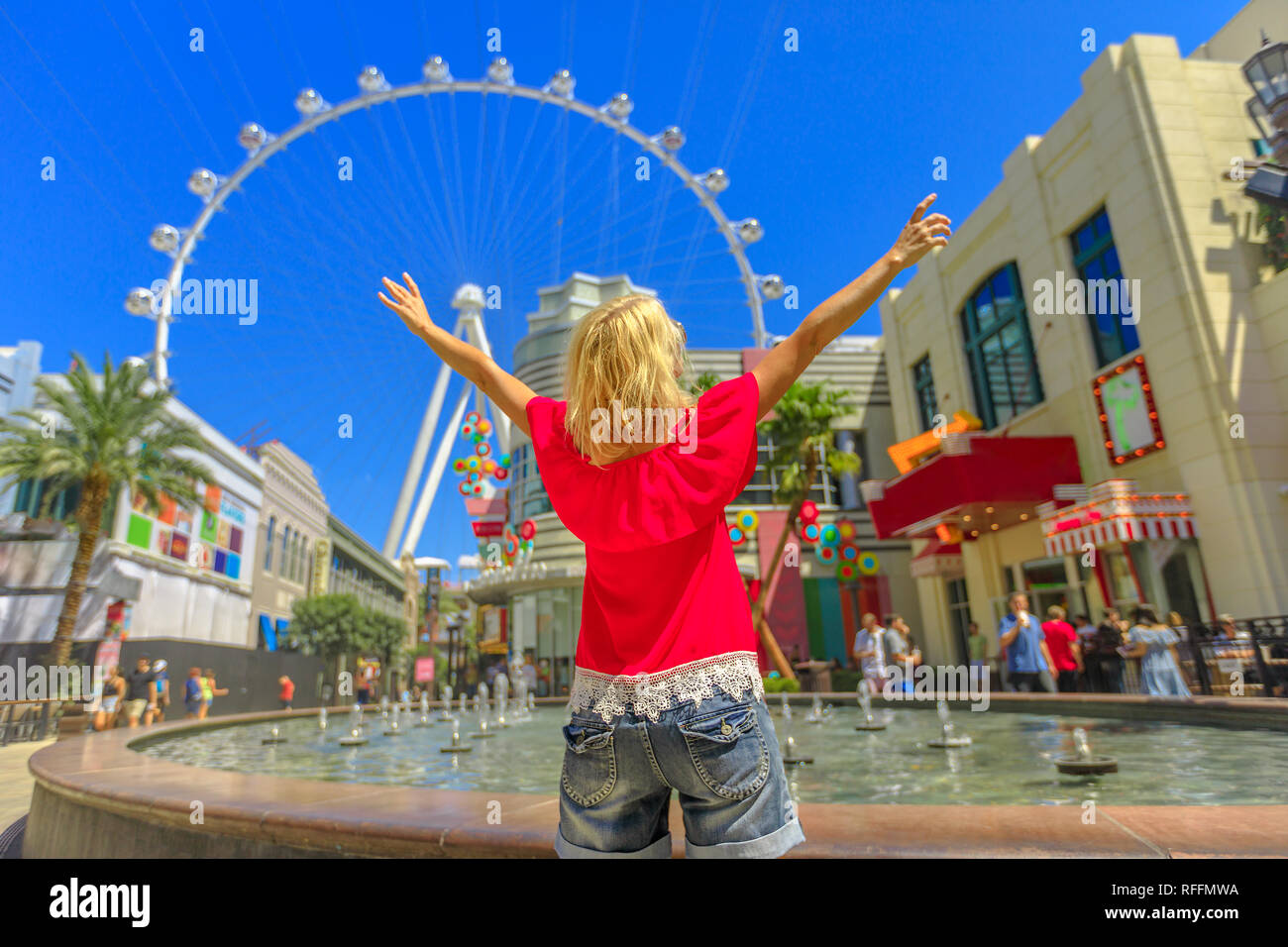 Donna bionda con i bracci sollevati cerchi ruota panoramica Ferris, il più grande del mondo ruota di osservazione al centro della Strip di Las Vegas. Felice turistico a Las Vegas Foto Stock