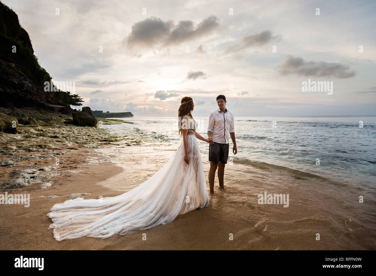 Sposa e lo sposo sulla spiaggia tenendo le mani guardando ogni altro Foto Stock