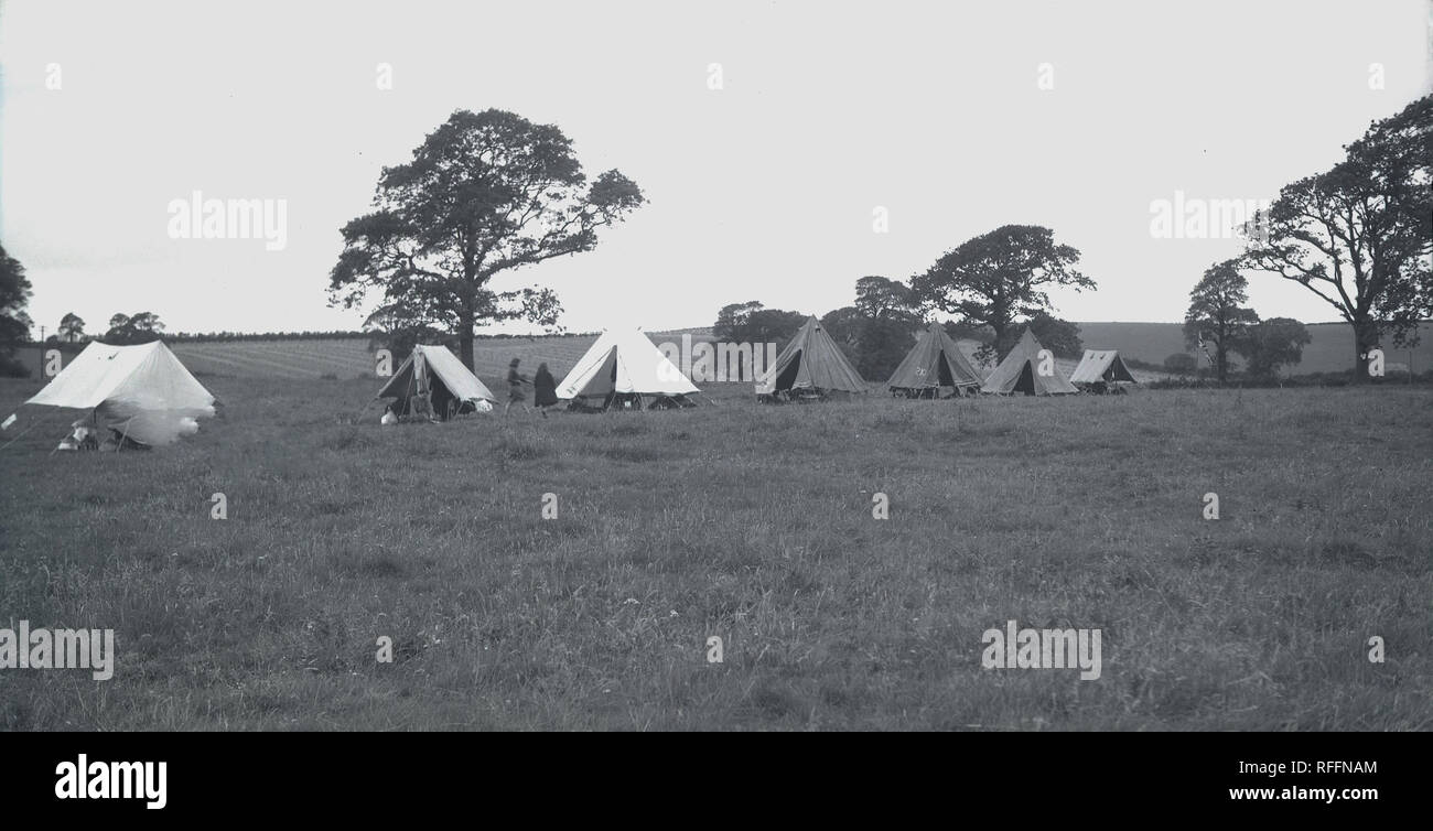 Degli anni Cinquanta, storici British girl guides campeggio in un campo erboso con tende, Inghilterra, Regno Unito. Foto Stock