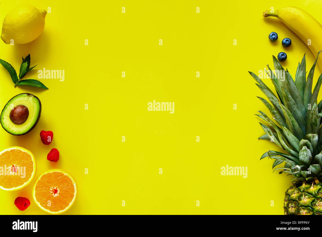 Layout creativi realizzati in vari frutti tropicali su sfondo giallo. Ananas, banana, arancio, limone, avocado, lampone e mirtillo. Concetto di cibo. F Foto Stock