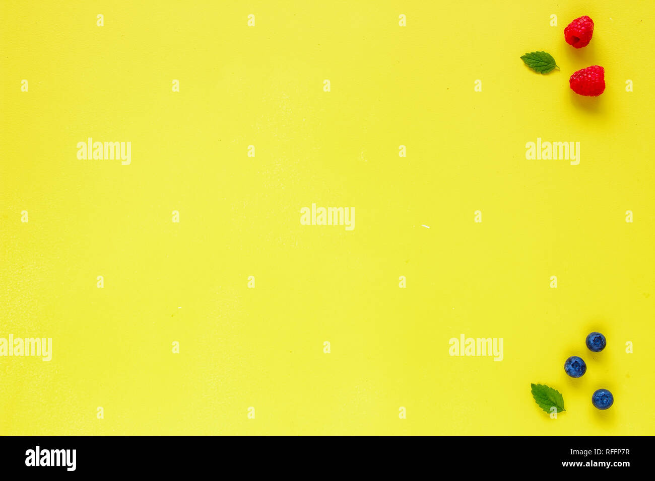 Layout creativo fatto di lampone, mirtillo e foglie di menta su sfondo giallo. Concetto di cibo. Piatto, laici vista superiore Foto Stock