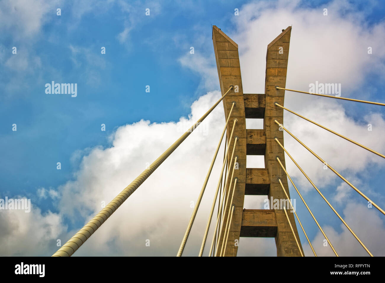 Sezione di un ponte sospeso a fune contro un cielo blu vibrante con nuvole bianche - ponte a pedaggio Lekki-Ikoyi, Lagos, Nigeria Foto Stock