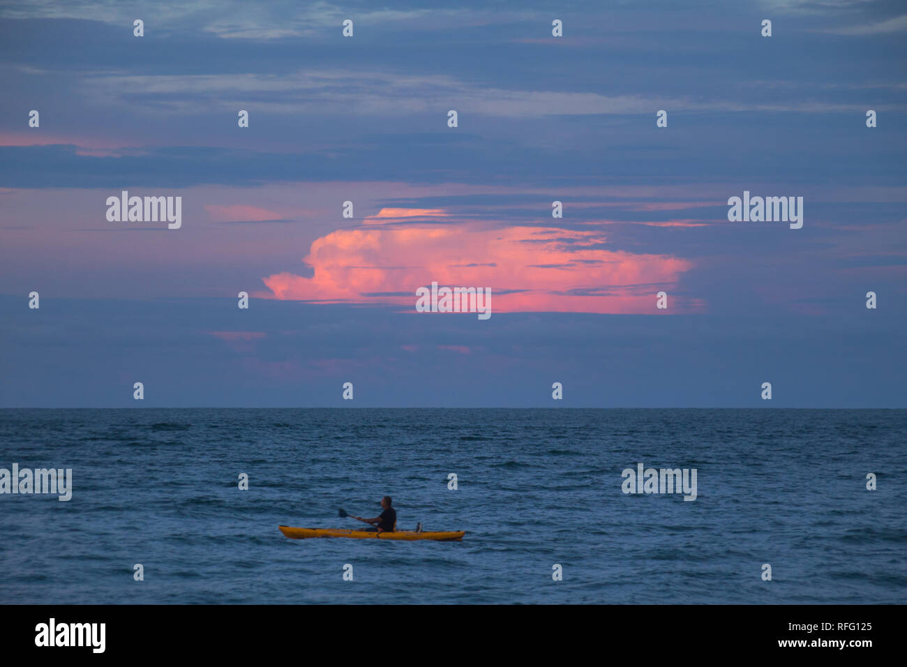 Un uomo solitario kayak di notte sullo sfondo di un bel colore rosa nuvole. Tramonto in Puerto Viejo, Costa Rica. Foto Stock