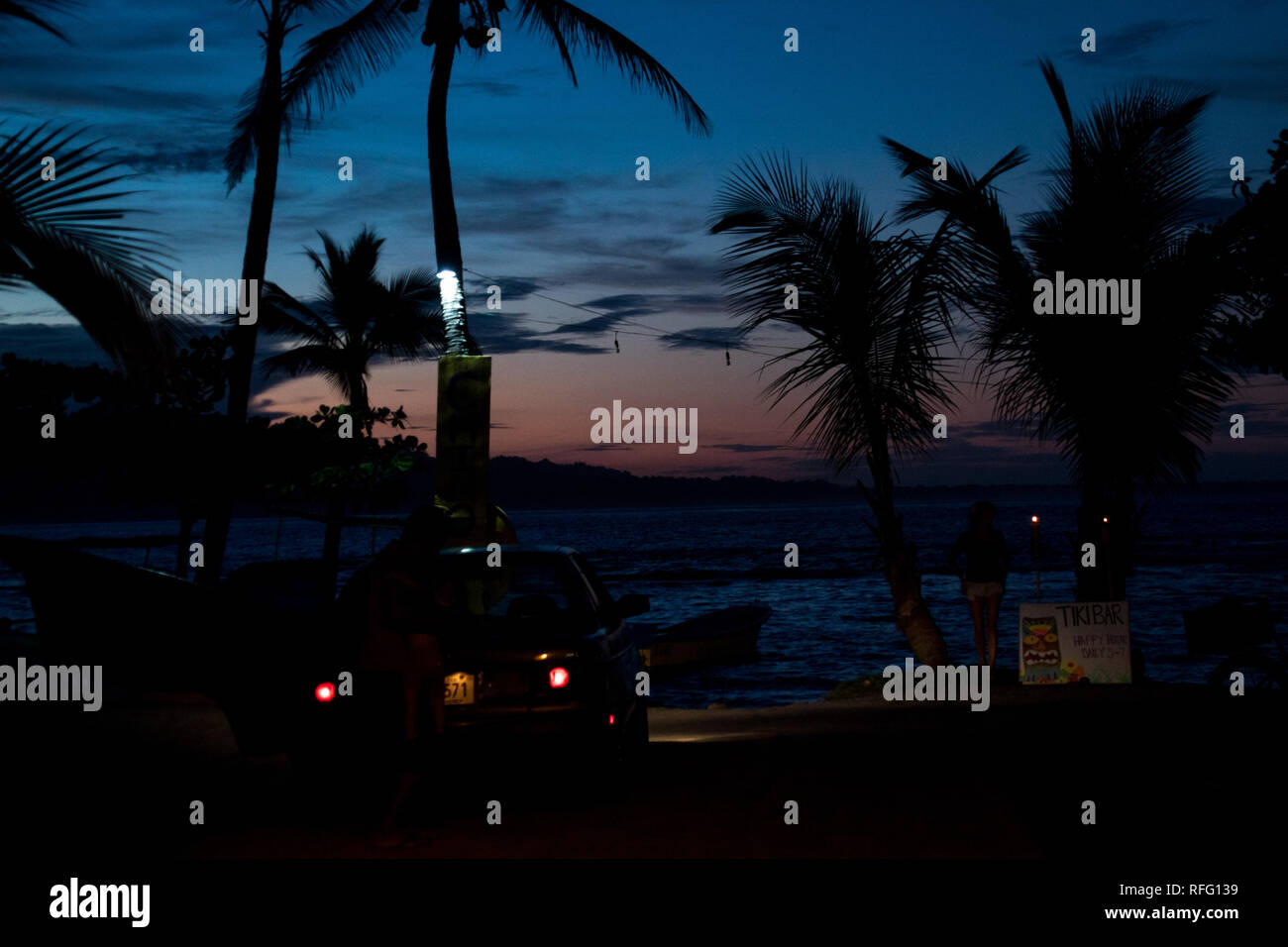 La foto di un parcheggio auto in una spiaggia durante un bellissimo tramonto. Sullo sfondo di splendide palme e il mare dei caraibi. Foto Stock
