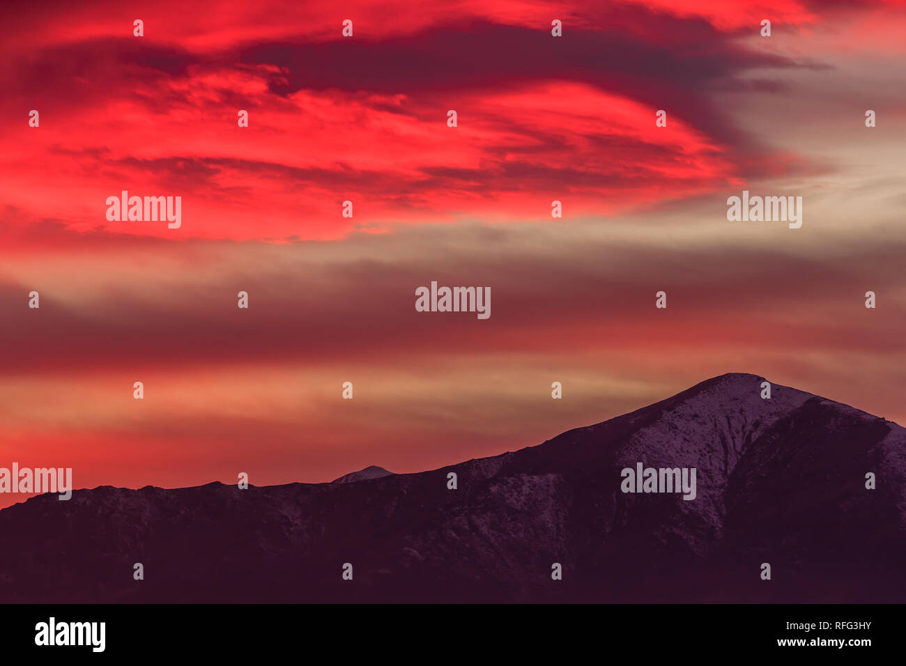 Un paesaggio al tramonto con le montagne disegnate nel cielo /una spettacolare red cloud al di sopra delle montagne Foto Stock