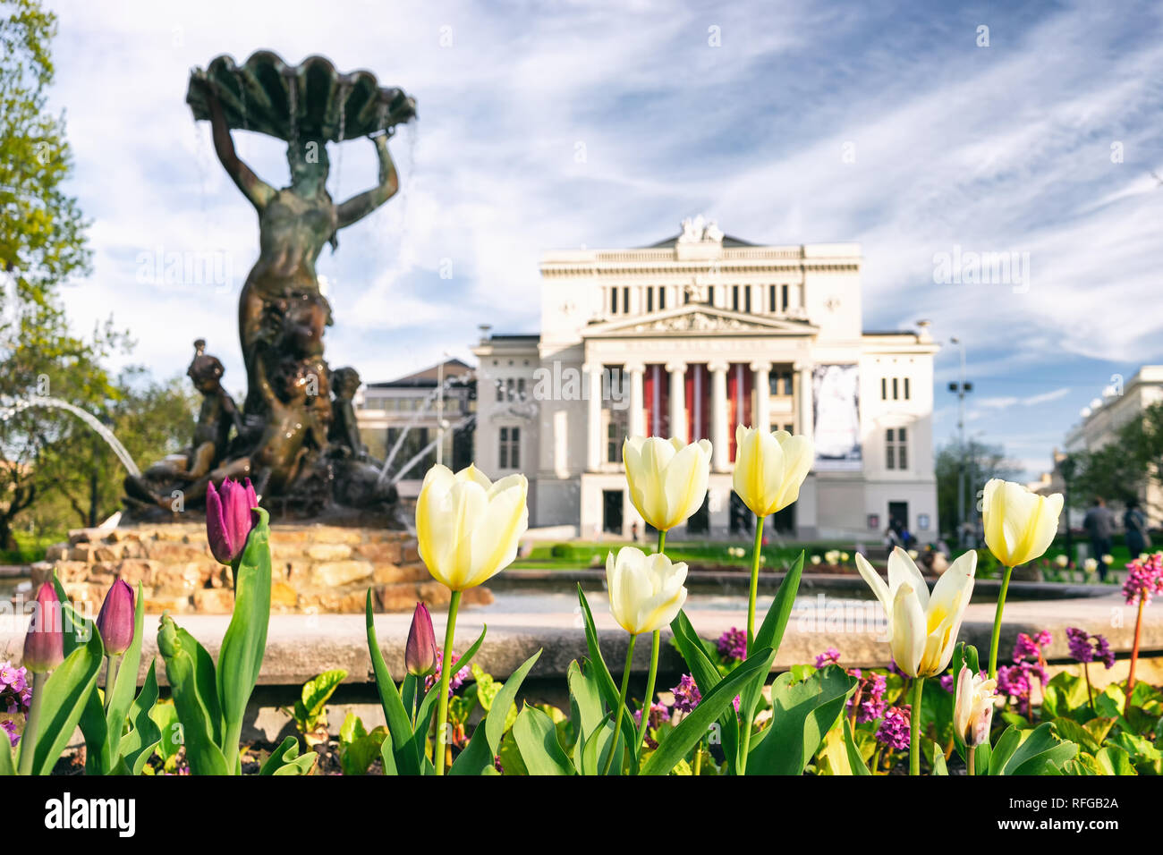 La costruzione del lettone del Teatro Nazionale di Opera e Balletto e tulipani nel parco contro lo sfondo della città Fontana Foto Stock