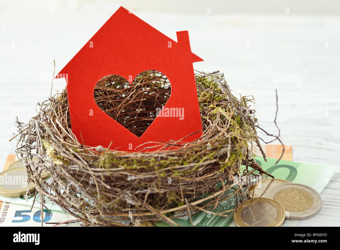 Casa carta con cuore nel nido su sfondo di denaro - amore per la casa, la casa di assicurazione nozione Foto Stock