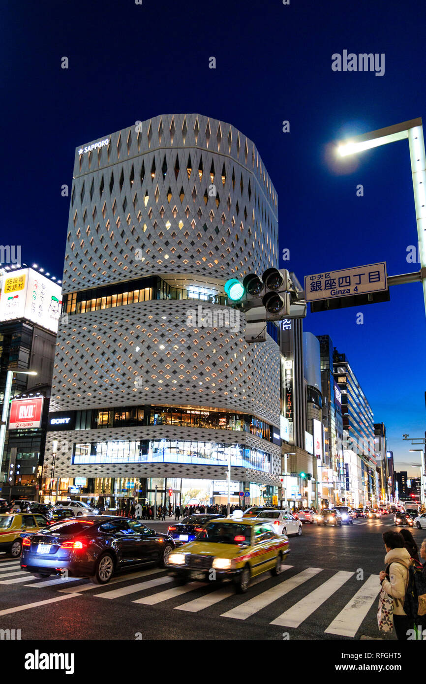 Il bianco Ginza luogo di costruzione in alluminio e la sua facciata del pannello. Di notte, la strada che attraversa in primo piano con Ginza 4 segno e luce di stop. Il traffico. Foto Stock
