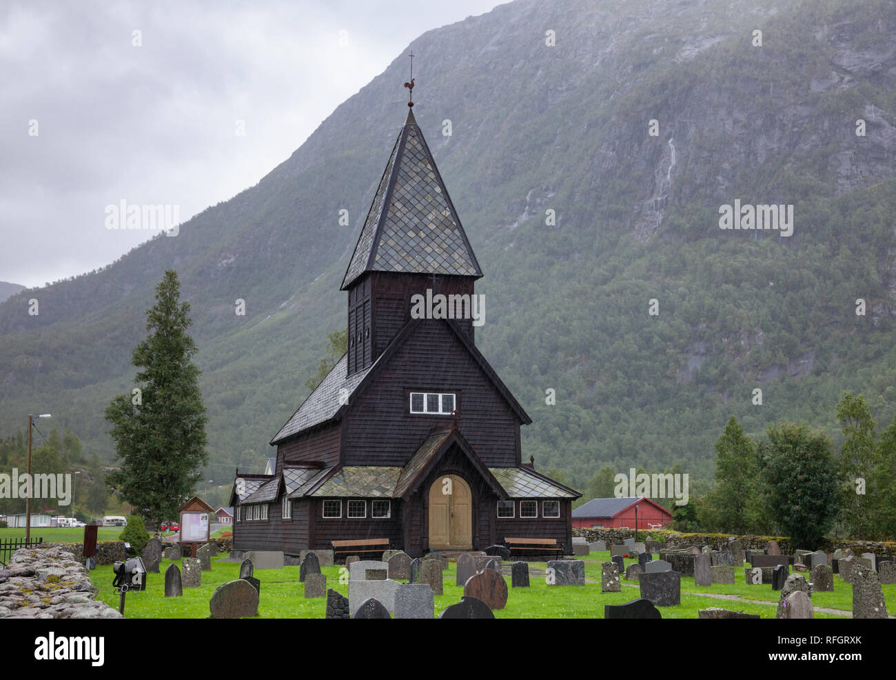 Xiii secolo Roldal in legno doga chiesa (Røldal stavkyrkje) e il cimitero in un giorno di pioggia, Odda, Hordaland, Norvegia, Scandanavia Foto Stock