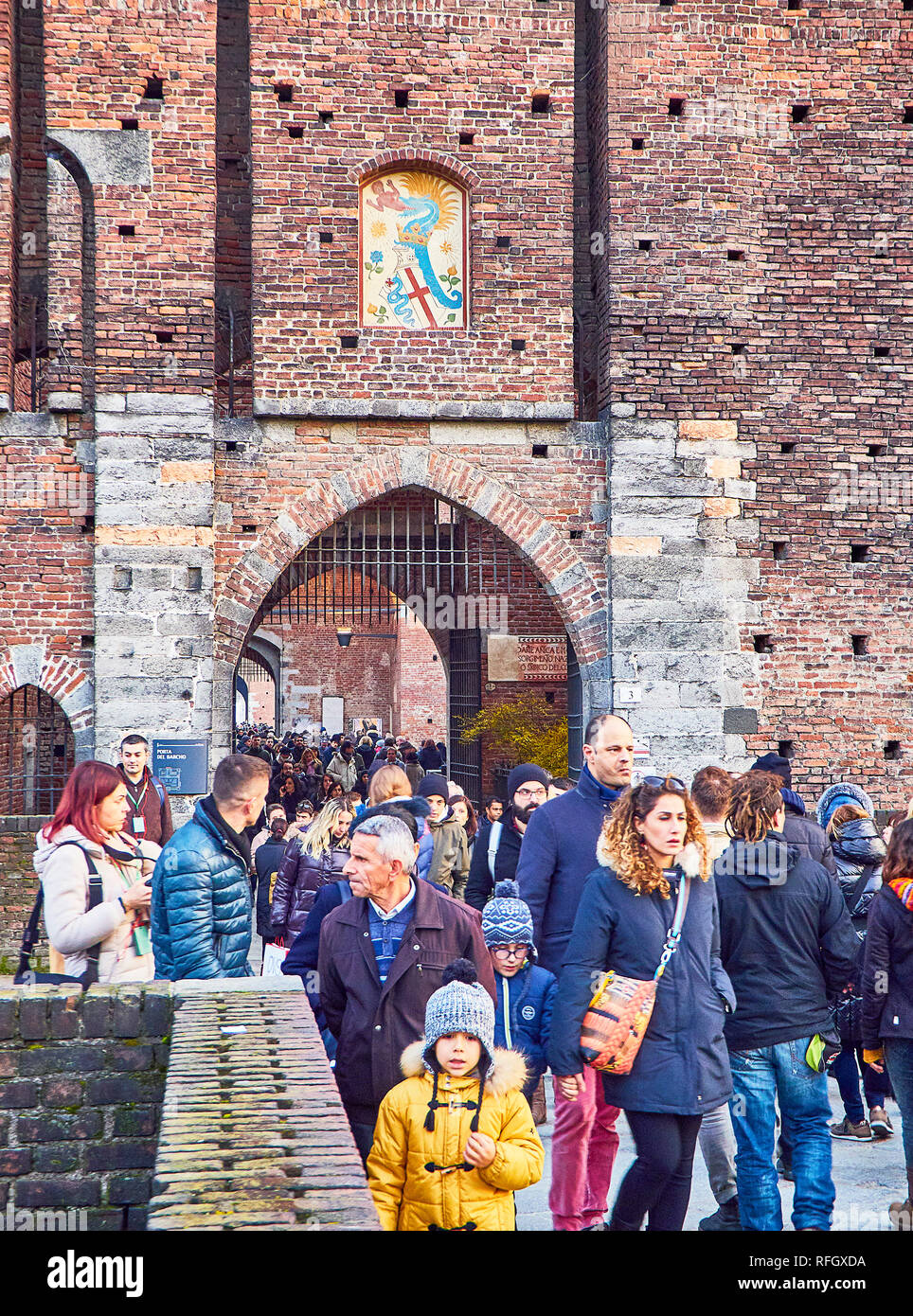 Turisti attraversando una delle porte del Castello Sforzesco, Castello Sforzesco, con lo stemma dei Visconti sui passaruota. Milano, lombardia, italia. Foto Stock