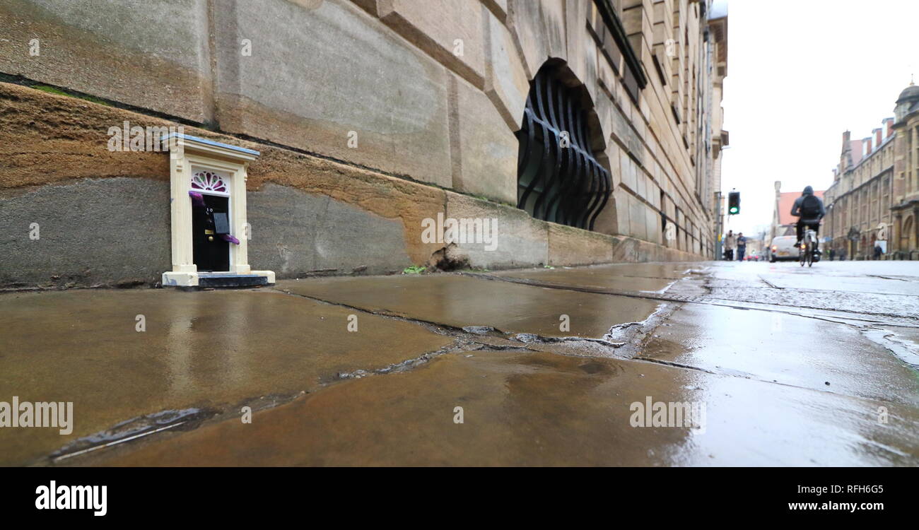 Cambridge, Regno Unito. 25 gennaio, 2019. Una piccola copia del famoso porta anteriore per il primo ministro britannico ha la residenza, n. 10 di Downing Street, Londra visto a Downing Street, Cambridge. Mistero gli artisti di strada che con lo pseudonimo di "inky porte' sono responsabili per l'installazione, che è la più recente di un progetto in corso. Ad oggi non vi sono 'dinky porte' alla realtà pedina su Parker's pezzo e il Teleport-O-Matic macchina tra telefono rosso scatole da la grande chiesa di Santa Maria in città. Credito: SOPA Immagini limitata/Alamy Live News Foto Stock