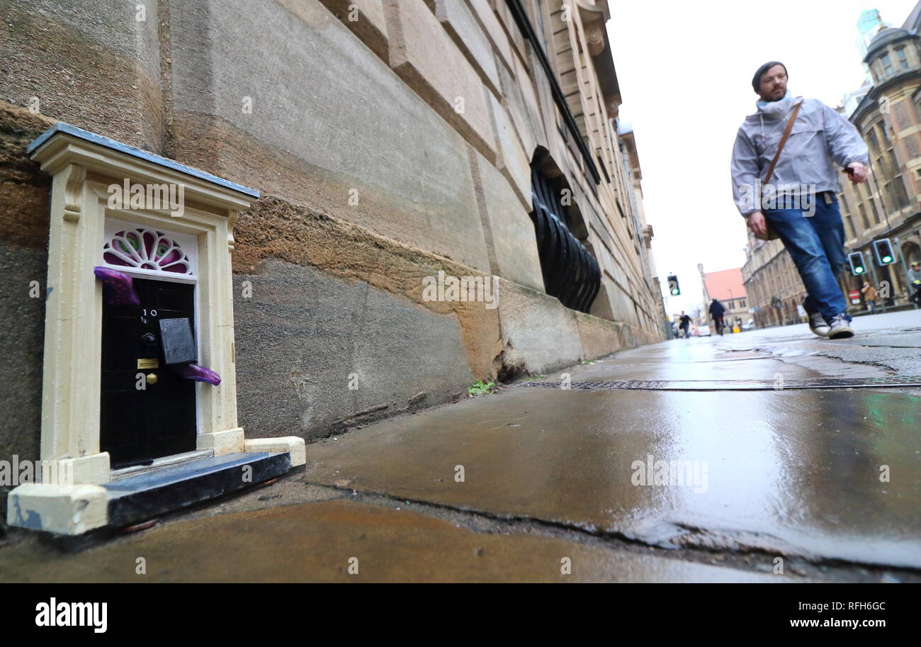 Cambridge, Regno Unito. 25 gennaio, 2019. Una piccola copia del famoso porta anteriore per il primo ministro britannico ha la residenza, n. 10 di Downing Street, Londra visto a Downing Street, Cambridge. Mistero gli artisti di strada che con lo pseudonimo di "inky porte' sono responsabili per l'installazione, che è la più recente di un progetto in corso. Ad oggi non vi sono 'dinky porte' alla realtà pedina su Parker's pezzo e il Teleport-O-Matic macchina tra telefono rosso scatole da la grande chiesa di Santa Maria in città. Credito: SOPA Immagini limitata/Alamy Live News Foto Stock