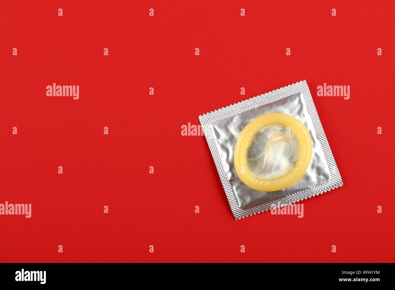 Chiudere un preservativo di lattice su argento wrap pack su vivid sfondo rosso con copia spazio, elevata angolo visuale, direttamente sopra Foto Stock