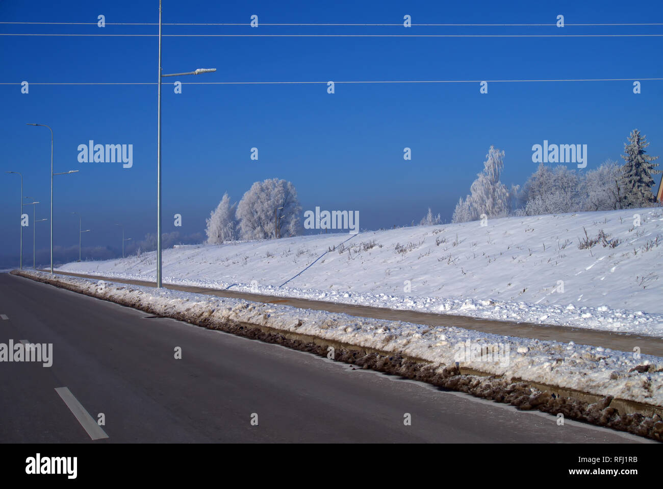 Snowy terrapieno a fianco di un'autostrada in un freddo sunny blue sky giornata invernale con neve coperti di alberi o lo skyline di un tempo e stagioni concept Foto Stock
