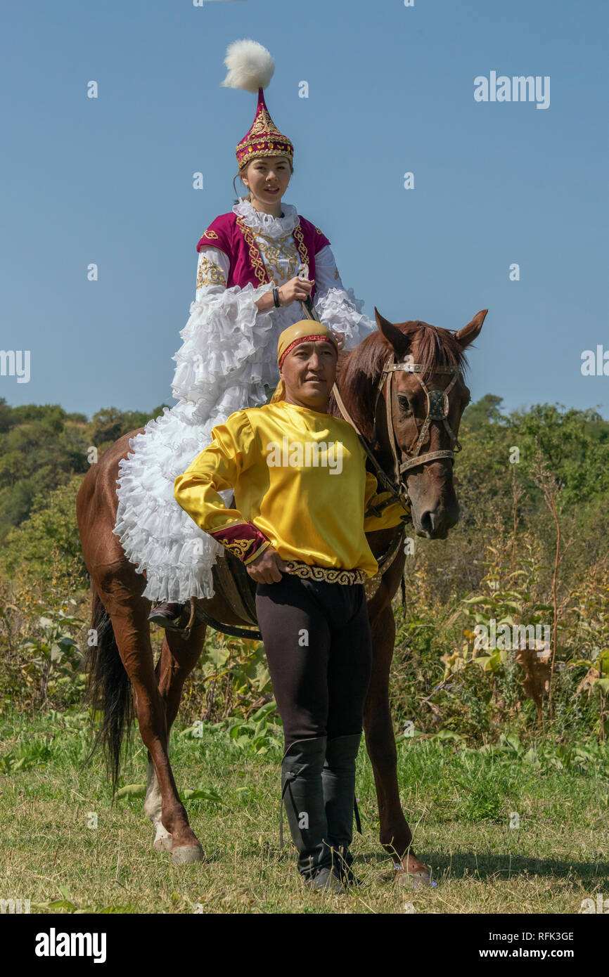 Il kazako giovane in abito tradizionale con il loro cavallo, Almaty, Kazakhstan Foto Stock